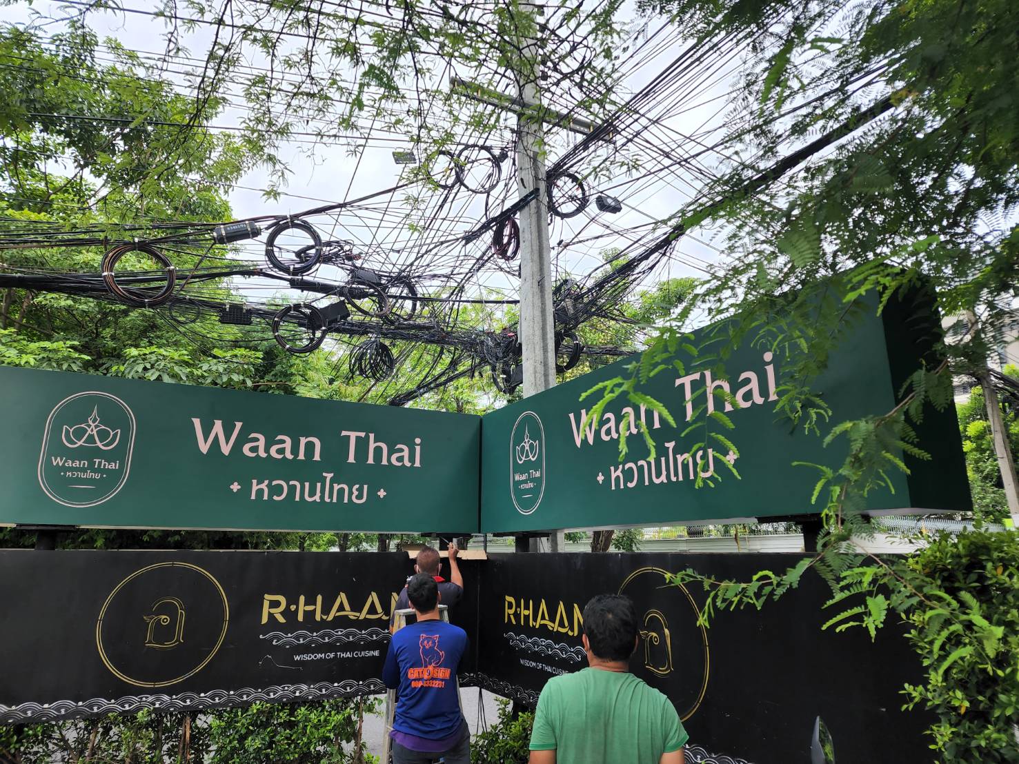 ป้ายร้านอาหาร Waan Thai หวานไทย และ R-HAAN สีเขียวขณะติดตั้งหน้าร้าน