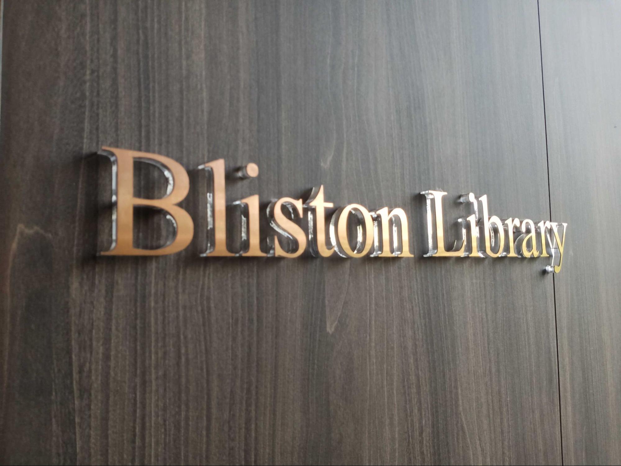 ป้ายชื่อห้อง Bliston Library ตัวอักษรสีทองบนผนังลายไม้สีเข้ม