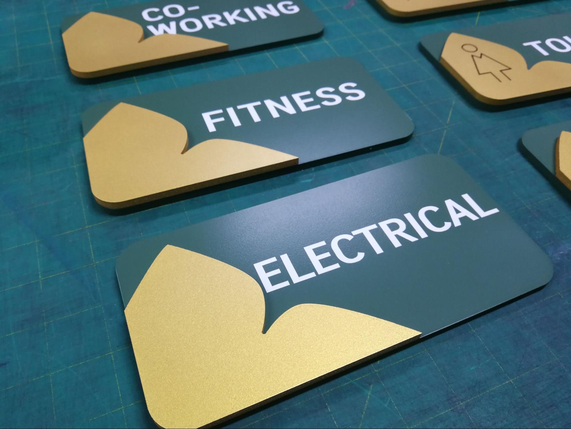 ป้ายบอกทางสิ่งอำนวยความสะดวกคอนโด CO-WORKING FITNESS ELECTRICAL TOILET สีเขียวทองพร้อมโลโก้ใบไม้