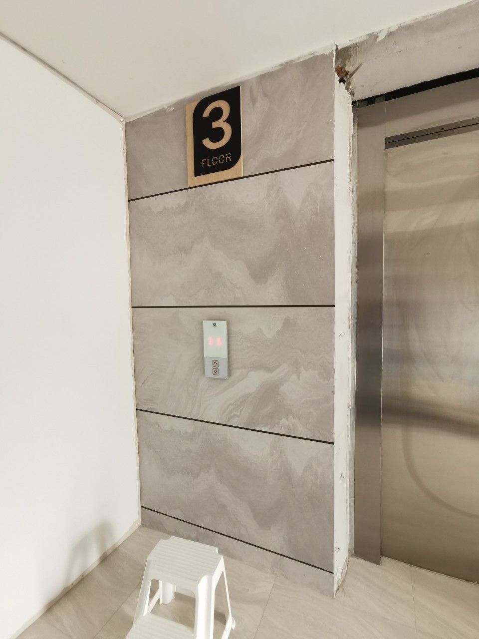 ป้ายบอกชั้น 3 Floor สีดำทอง ติดตั้งข้างลิฟต์บนผนังหินอ่อนสีเทา