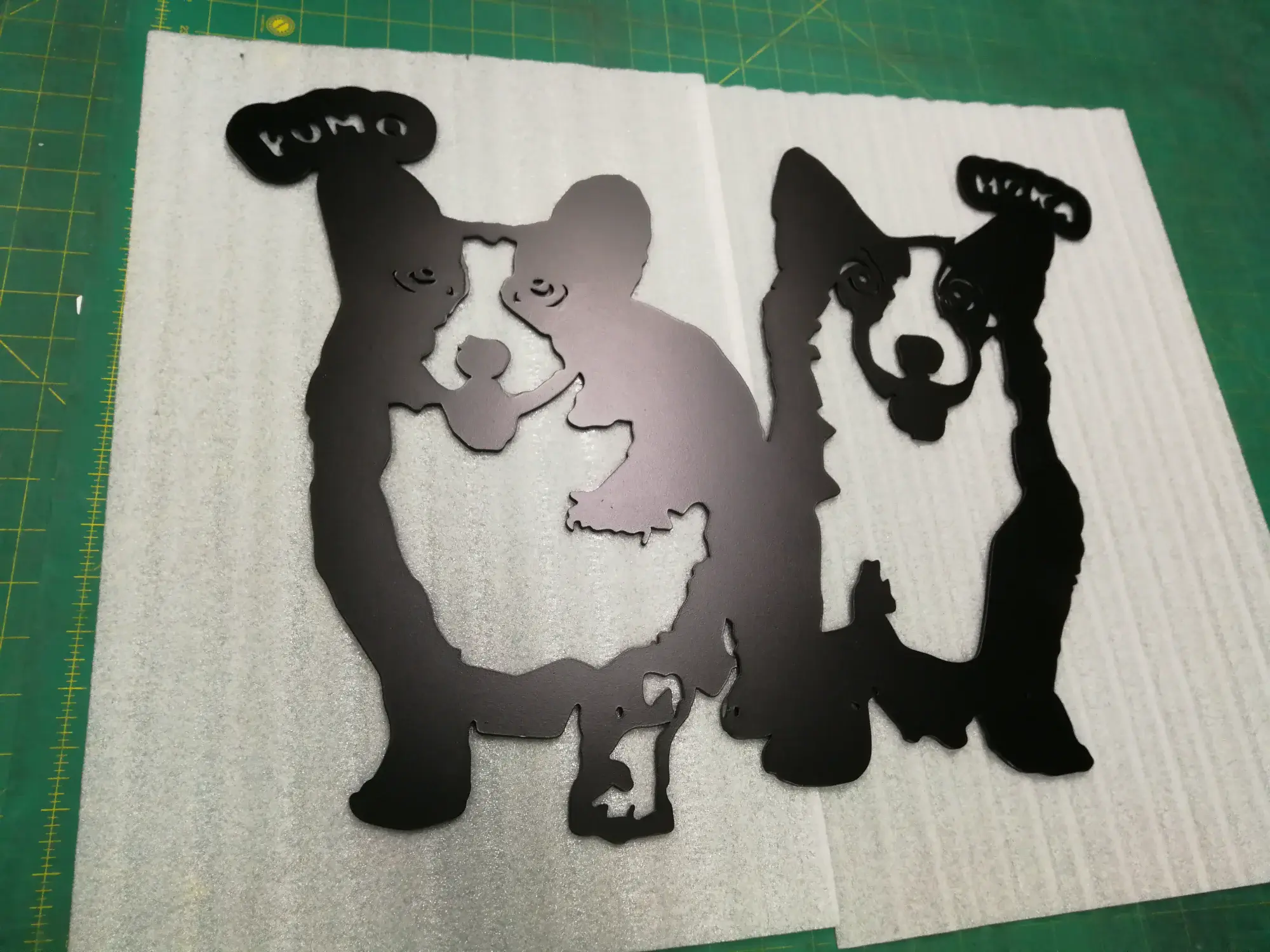 แผ่นสแตนเลสสีดำฉลุรูปสุนัขคอร์กี้ PUMO และ MOKA พร้อมแผ่นสำรองบนโต๊ะตัด