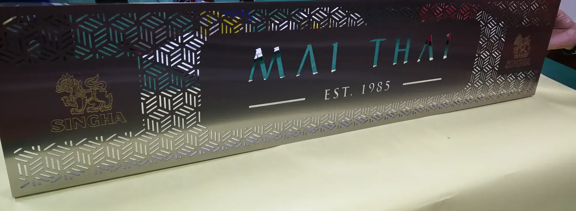 ป้ายสแตนเลสแฮร์ไลน์ MAI THAI EST. 1985 โลโก้สิงห์ฉลุลายไทยประยุกต์