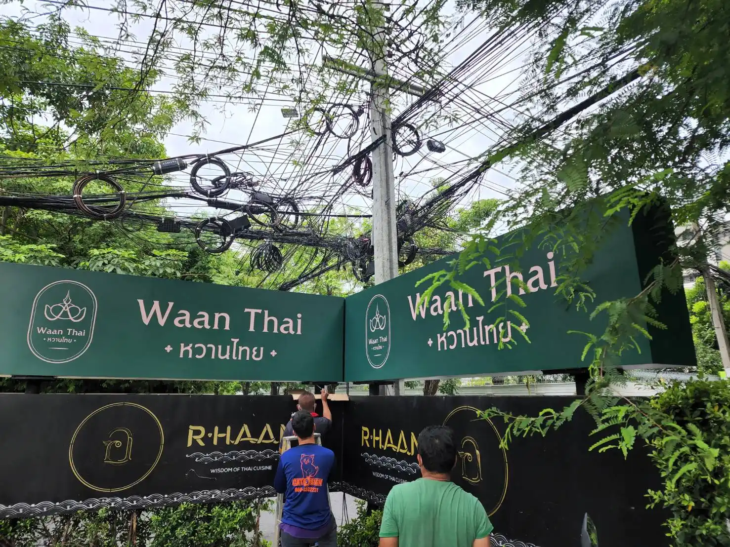 ป้ายสแตนเลสร้านอาหาร Waan Thai หวานไทย และ R-HAAN พื้นเขียวดำระหว่างติดตั้ง