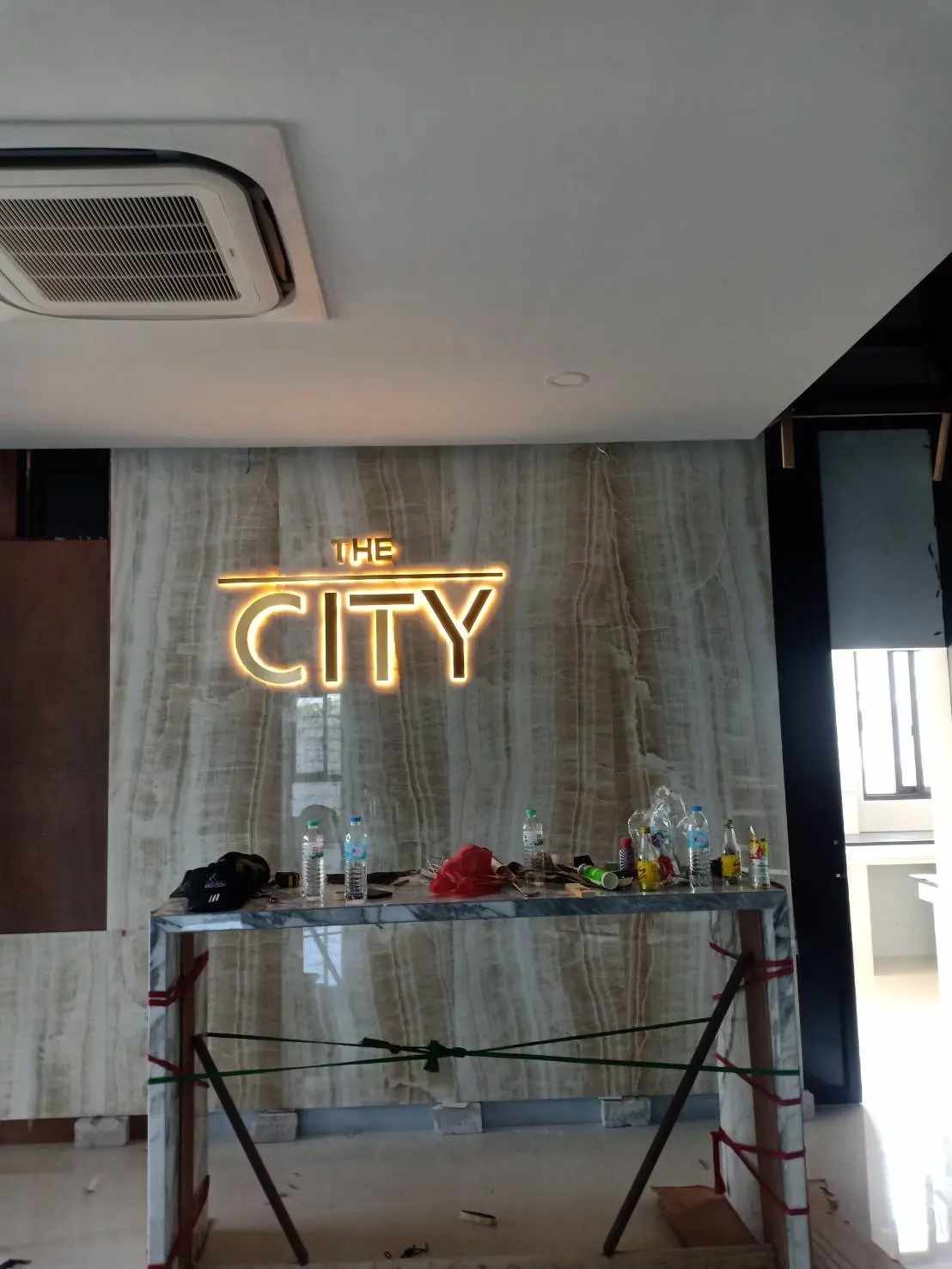 ป้ายชื่อคอนโด The City ตัวอักษรสแตนเลสสีทองมีไฟส่องสว่าง ติดตั้งบนผนังหินอ่อนในล็อบบี้