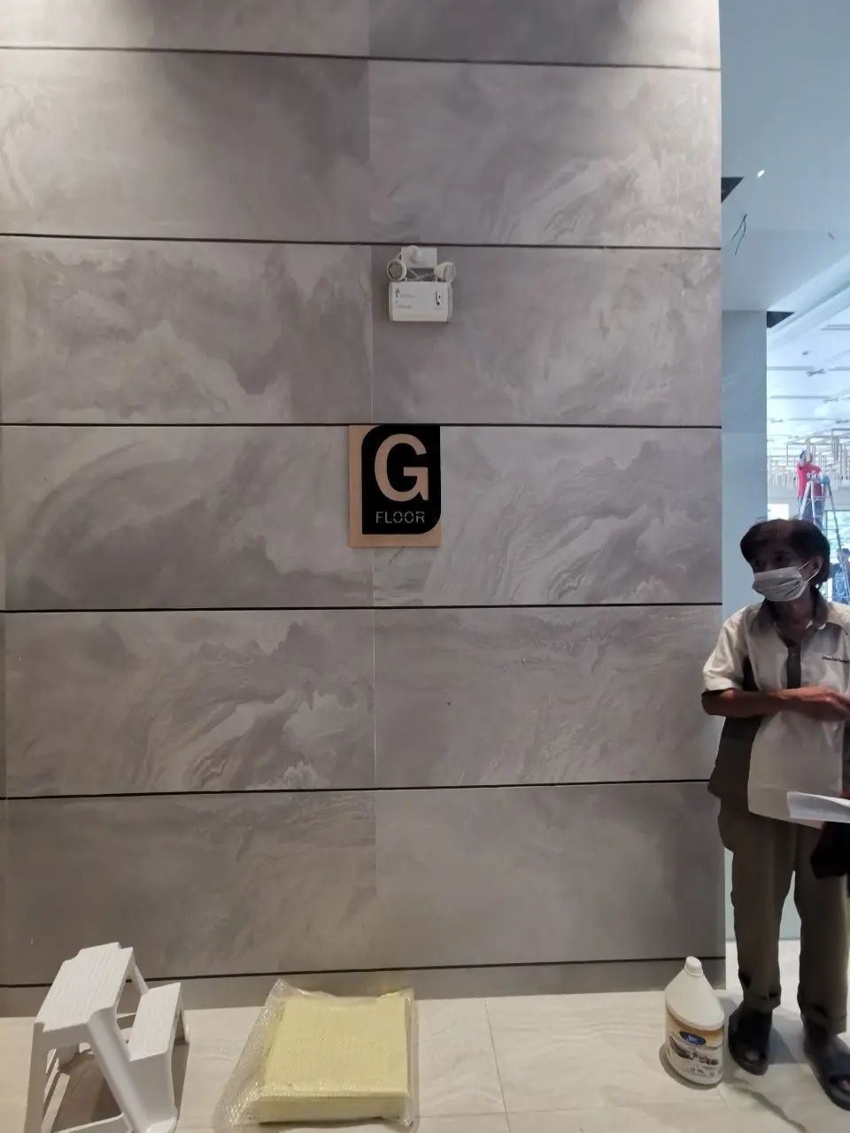 ป้ายบอกชั้น G FLOOR สีดำตัวอักษรครีม ติดตั้งบนผนังหินอ่อนระหว่างติดตั้ง