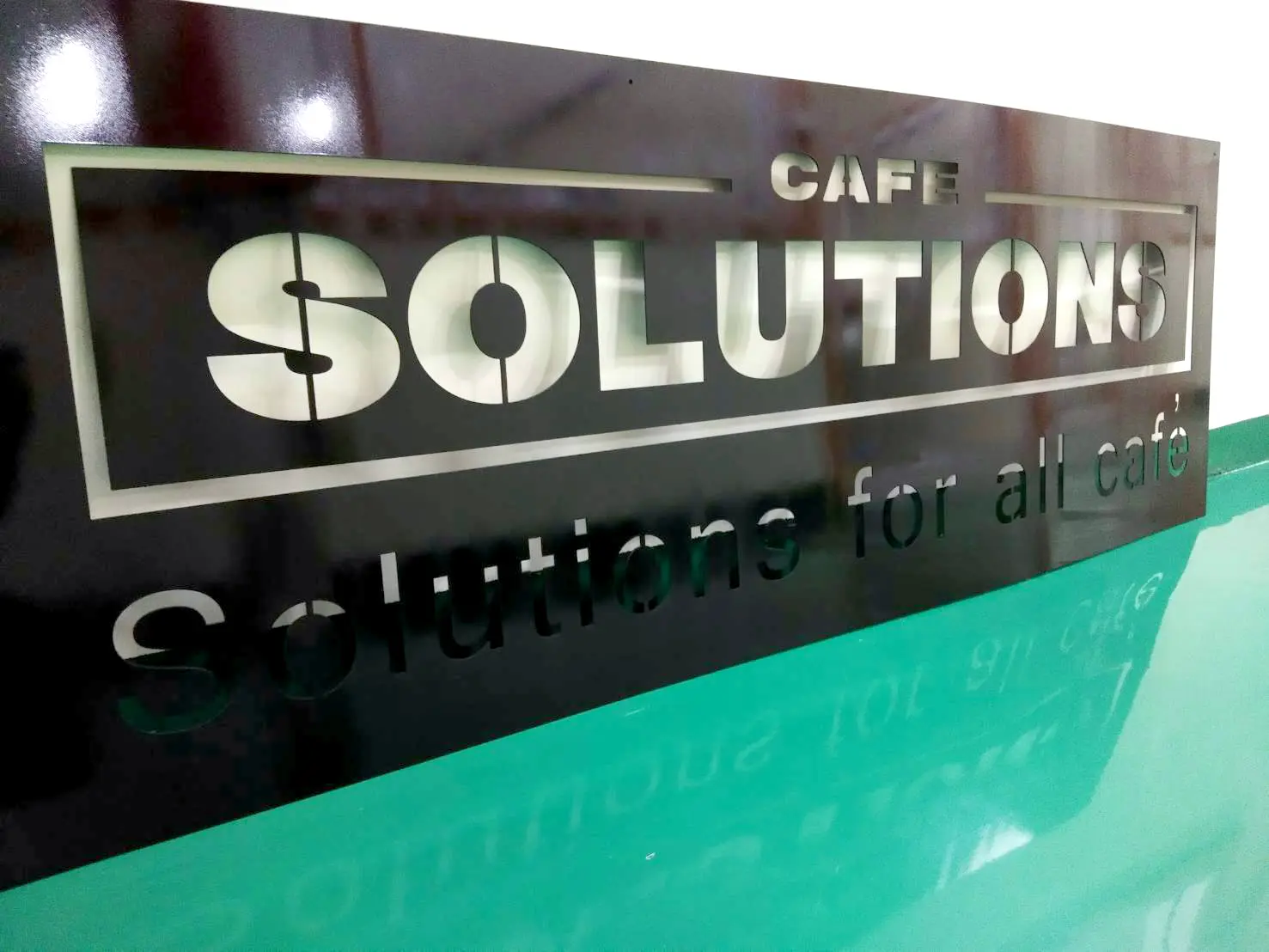 ป้ายสแตนเลสแฮร์ไลน์ CAFE SOLUTIONS Solutions for all café บนแผ่นอะคริลิกดำ