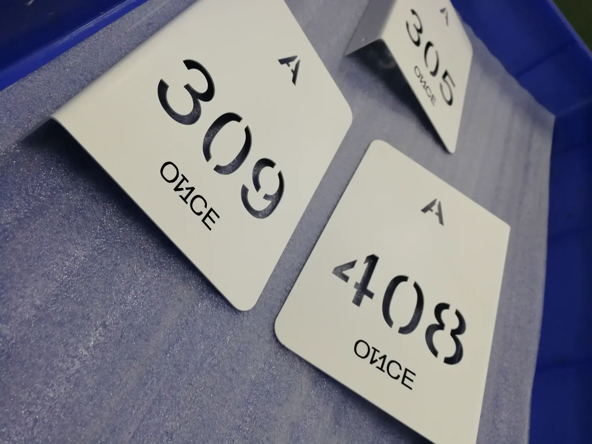 ป้ายเลขห้องสแตนเลสพ่นสีขาวฉลุเลข A 309 A 408 A 305 OFFICE วางในถาดโรงงาน