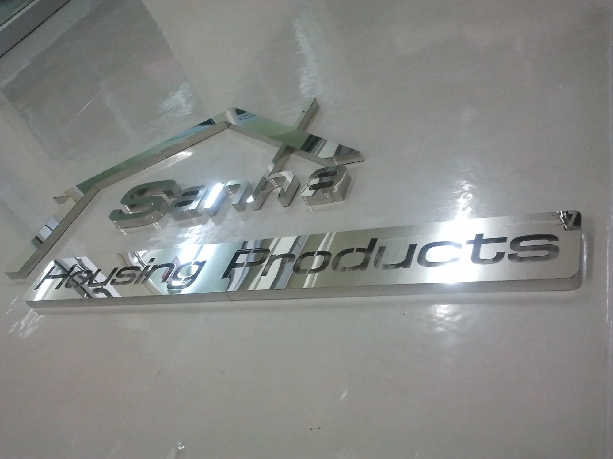 ป้ายสแตนเลสมิเรอร์โลโก้ Sanwa Housing Products รูปหลังคาบ้านติดผนังล็อบบี้