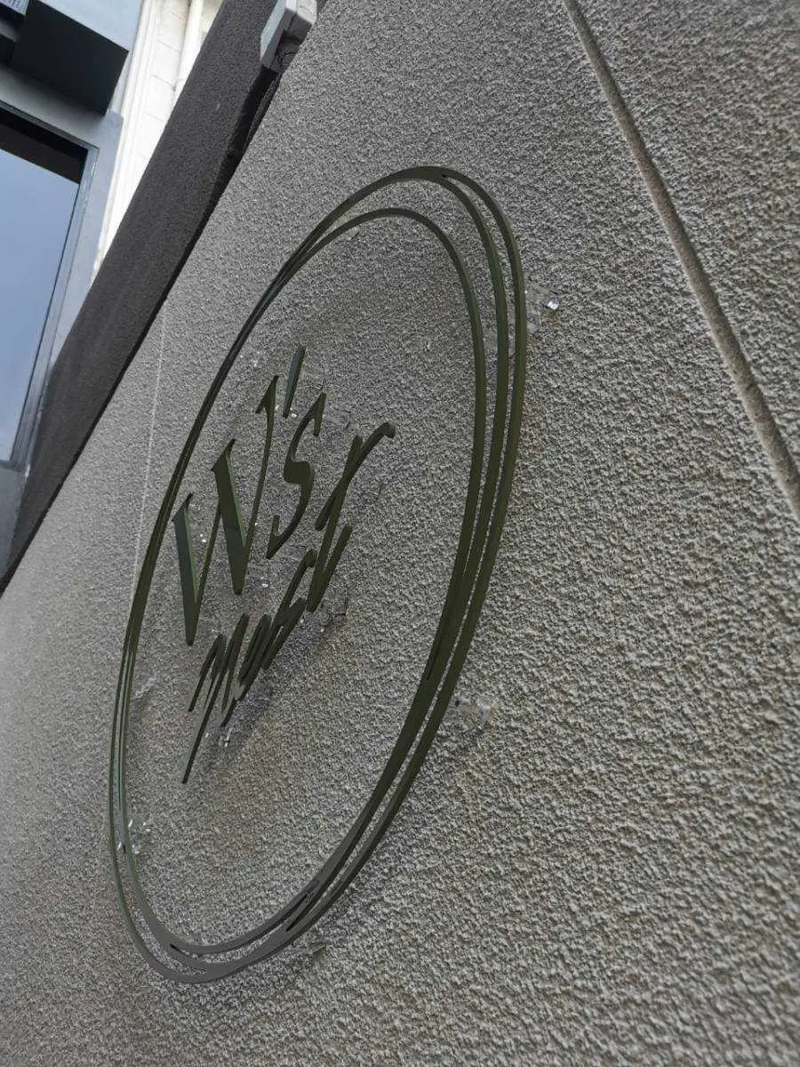 โลโก้สแตนเลสแฮร์ไลน์ W's mark ทรงวงรีลายมือเขียนติดผนังปูนเปลือย