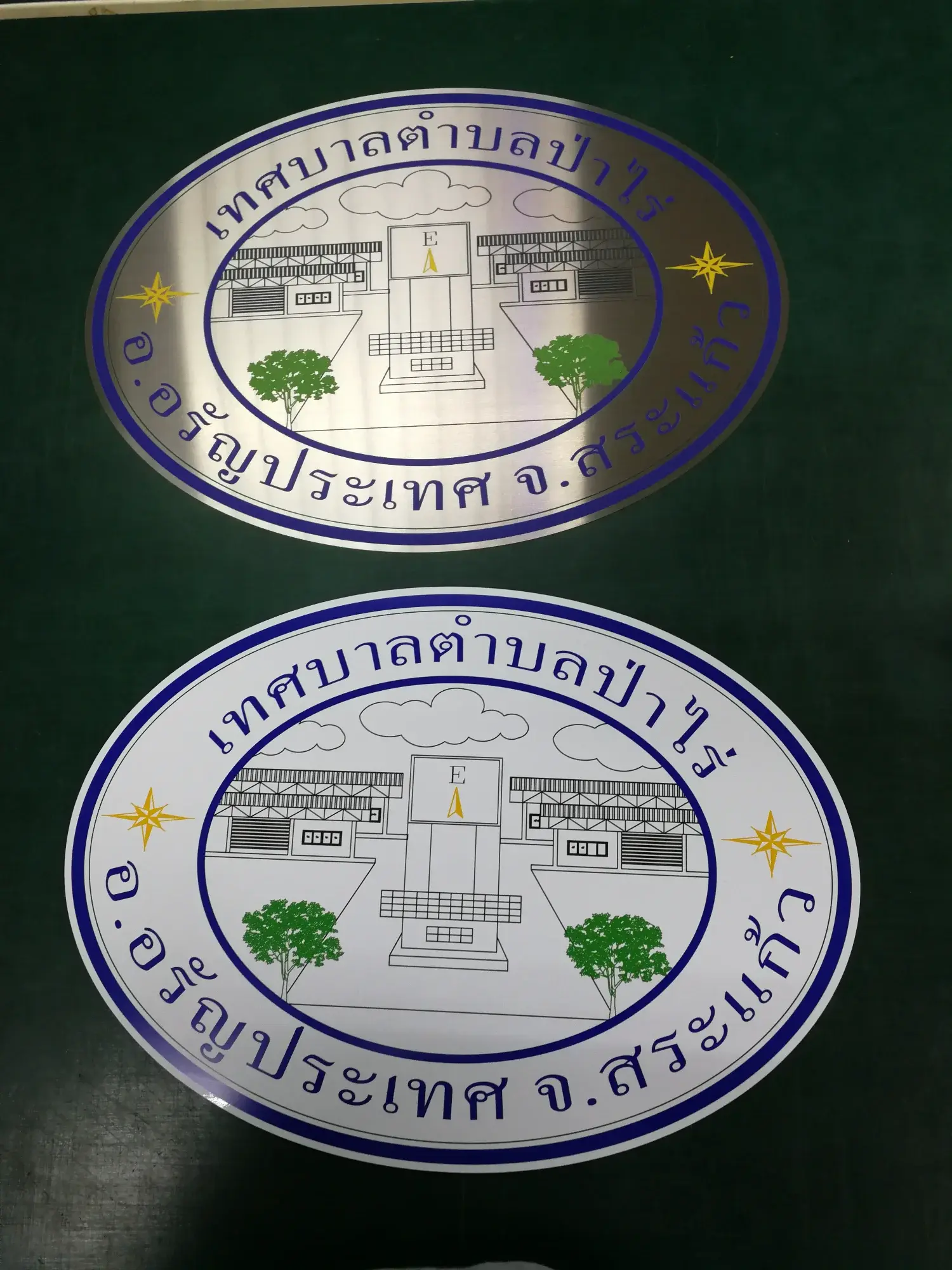 ป้ายตราสัญลักษณ์เทศบาลตำบลป่าไร่ อ.อรัญประเทศ จ.สระแก้ว รูปอาคารและพระพุทธรูปทอง วงรีขอบน้ำเงิน