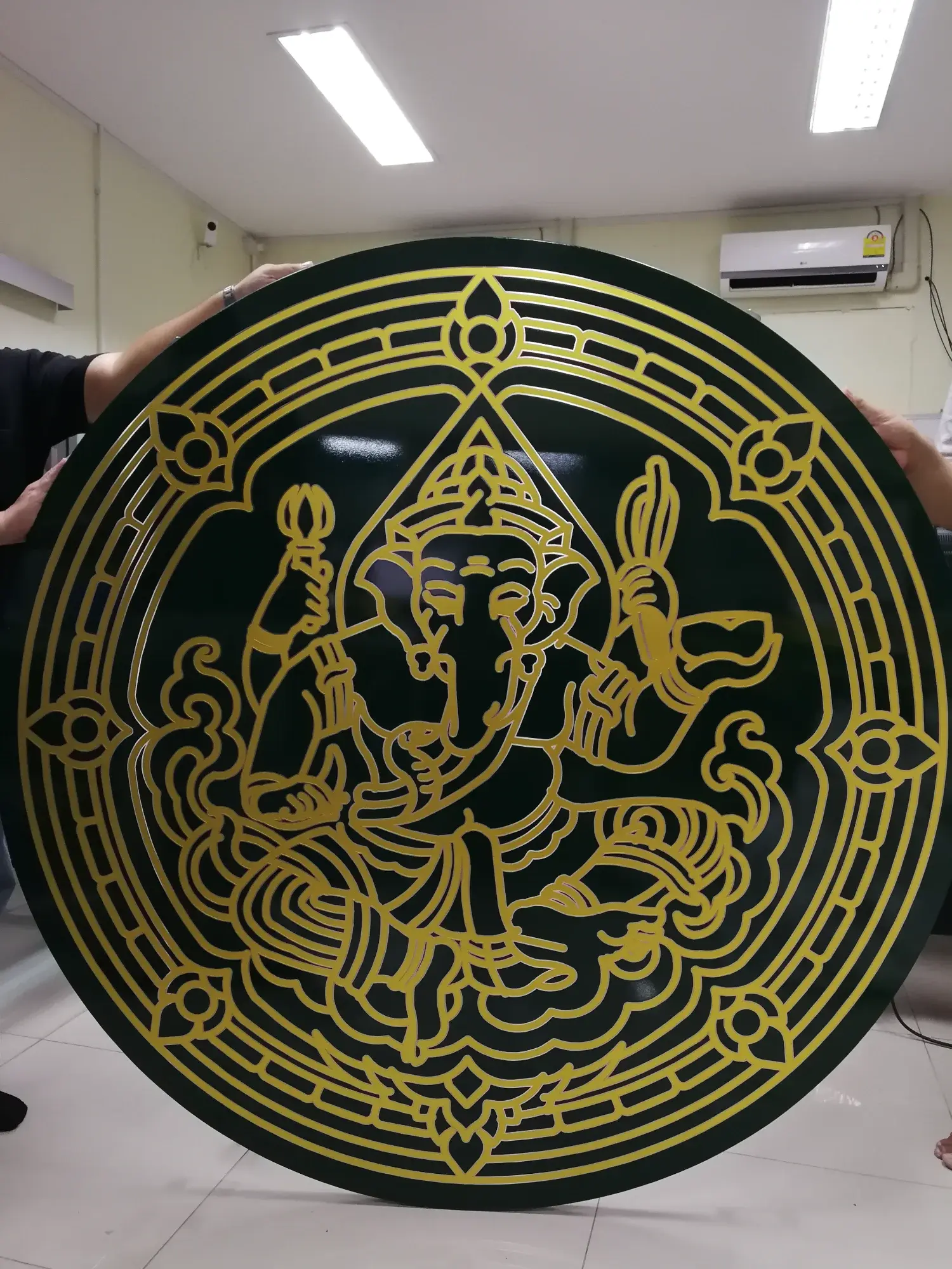 ป้ายตราสัญลักษณ์พระพรหมสี่หน้าทองเหลืองตัดลายบนพื้นสีเขียวเข้ม ขนาดใหญ่วงกลมพร้อมขอบลายไทย