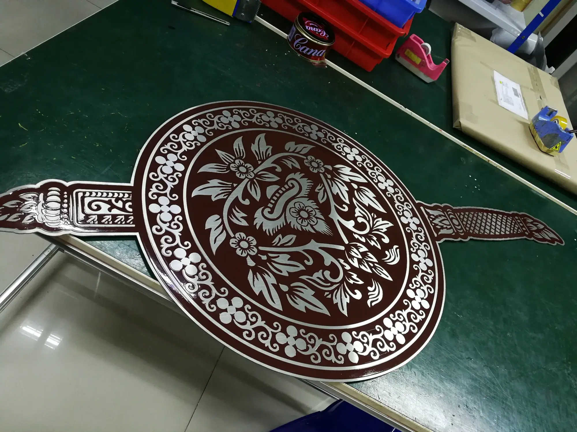 ป้ายพัดยศสแตนเลสลายดอกไม้ไทยสีเงินบนพื้นแดงเข้ม พร้อมด้ามจับลวดลายไทยสองข้าง