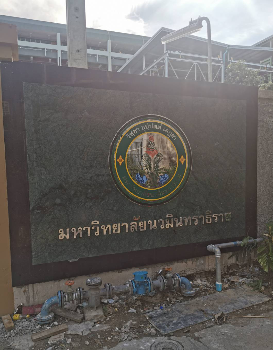ป้ายมหาวิทยาลัยนวมินทราธิราช พร้อมตราสัญลักษณ์และตัวอักษรภาษาไทย