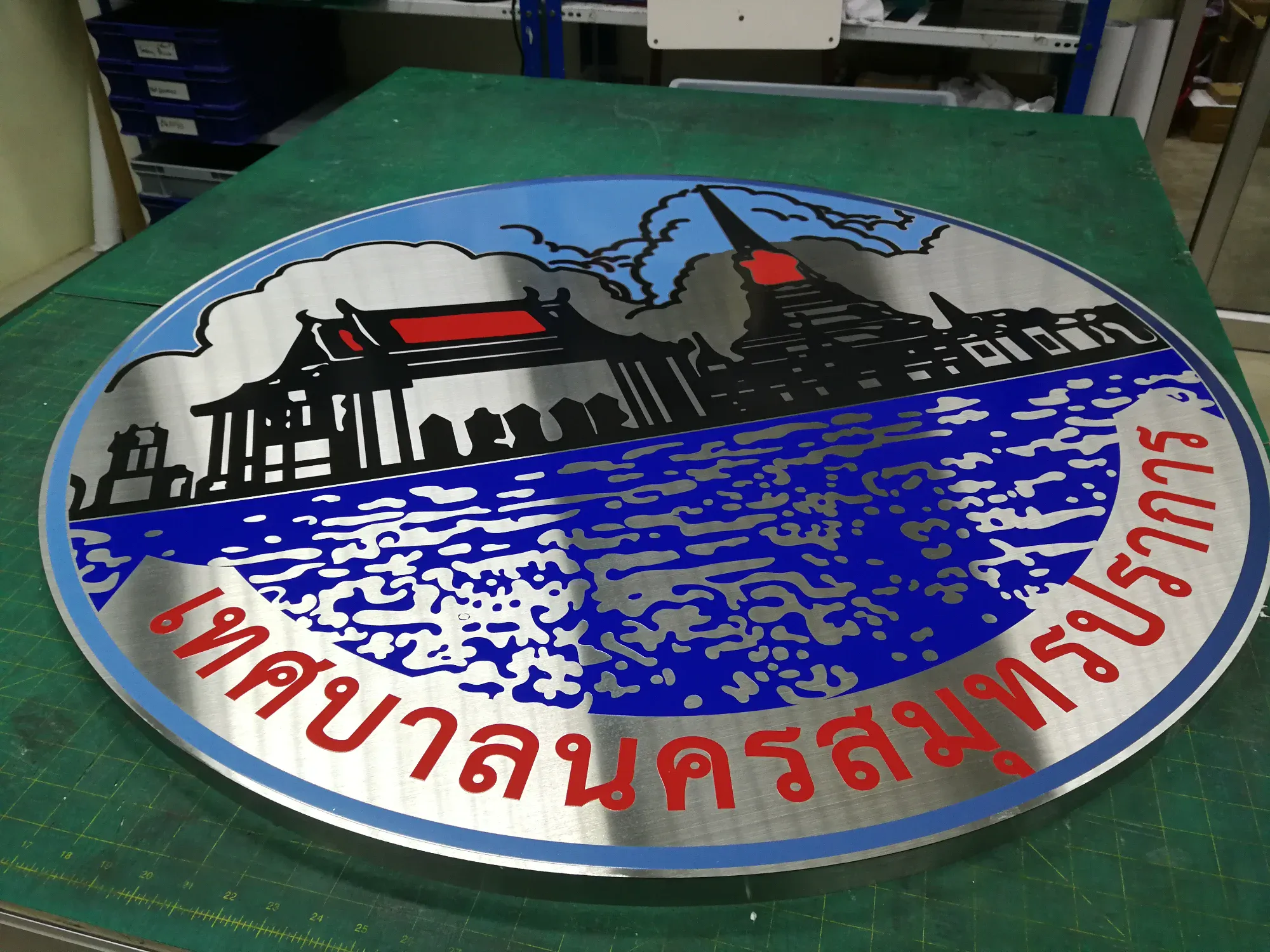 ป้ายตราสัญลักษณ์เทศบาลนครสมุทรปราการ สแตนเลส รูปทิวทัศน์วัดและเจดีย์ริมน้ำสีน้ำเงิน